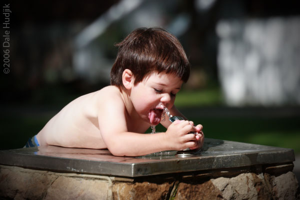 A little boy drinking from a water fountain